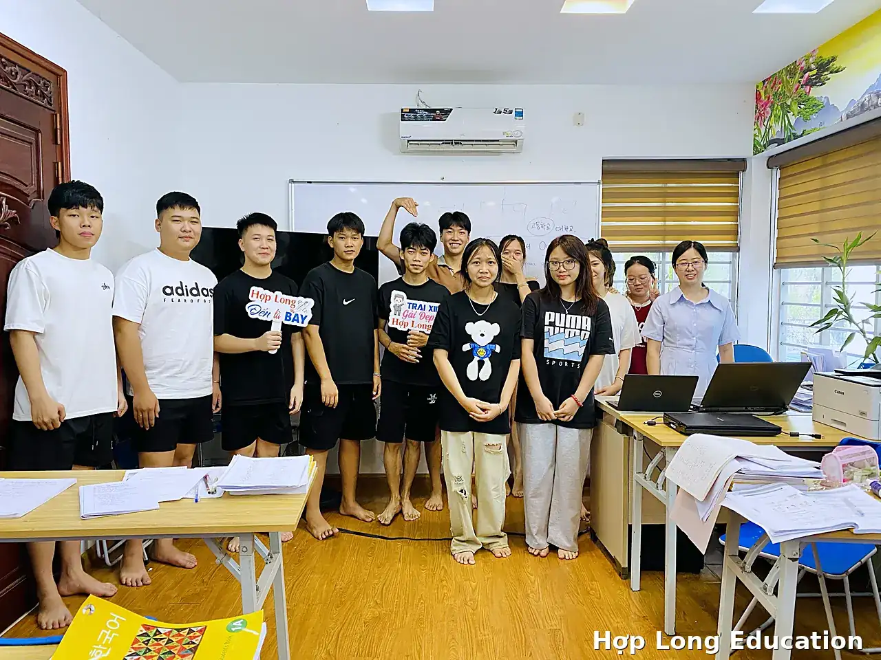 Học viên Hợp Long chụp ảnh nhóm trong phòng học, vài bạn cầm biển Hợp Long đến là bay